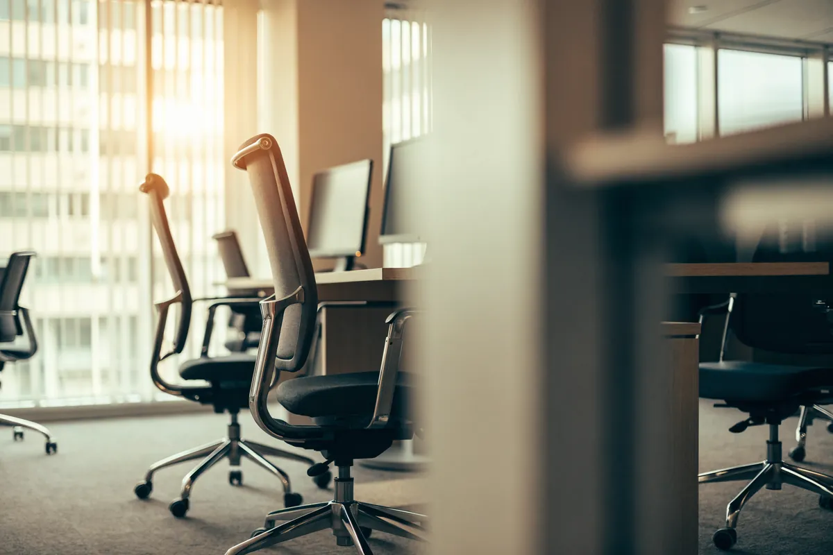 Escritorios y sillas de oficina vacíos, con puestos sin cubrir